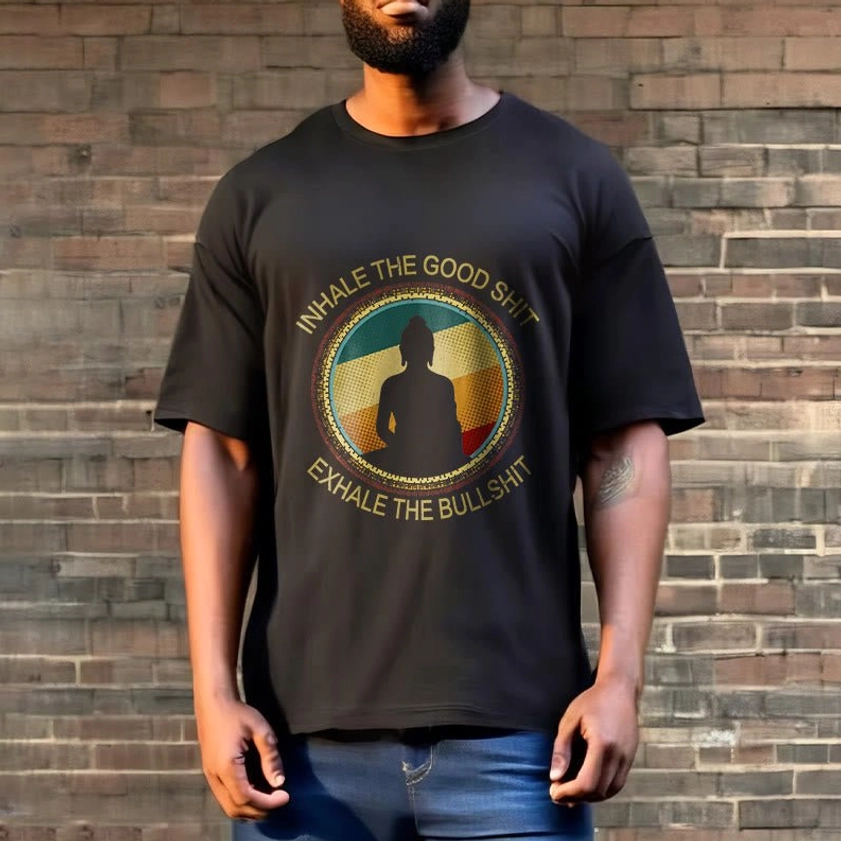 Man in vintage Buddhist meditation t-shirt posing against brick wall outdoor setting, full torso view