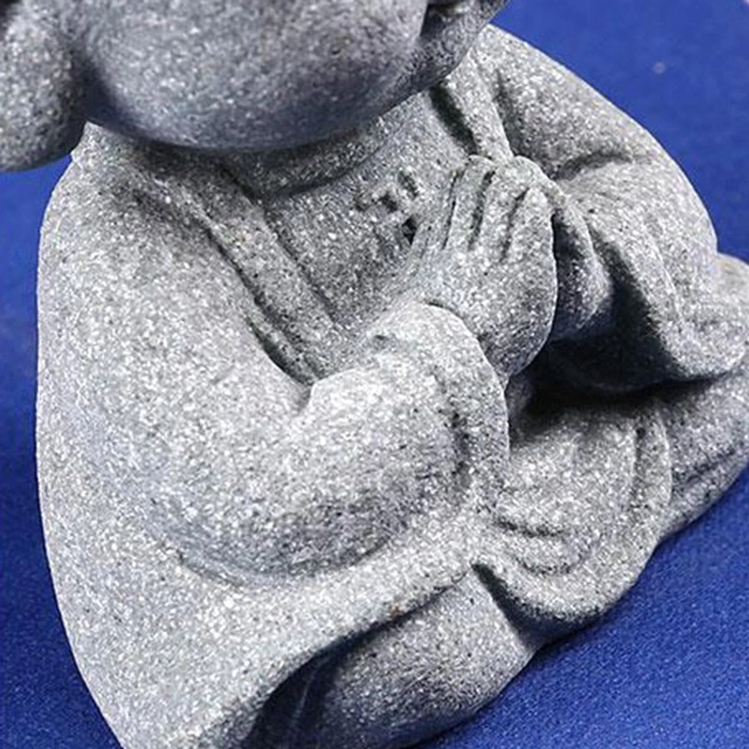Close-up side view of Buddha torso showing robe texture and clasped prayer hands in natural grey sandstone