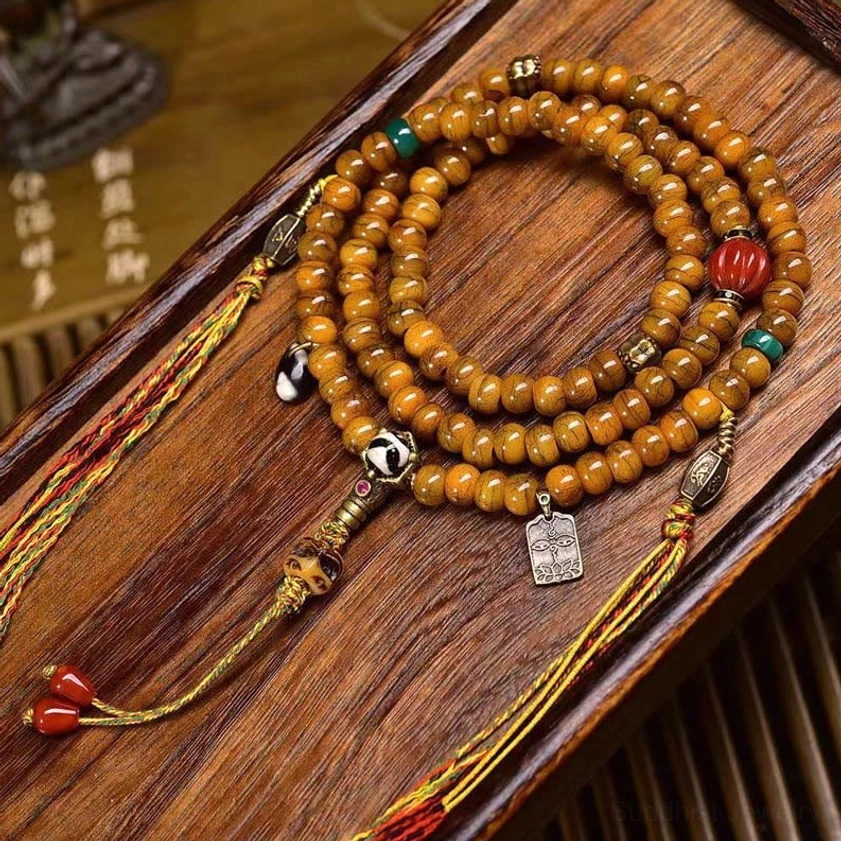 108-bead Buddhist prayer mala with hand-painted Dzi beads, bone barrel beads, turquoise and red accents, silver guru bead and tassel on wooden surface