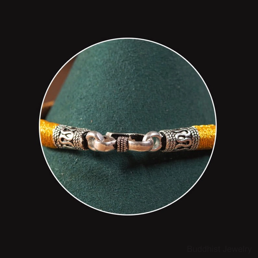 Buddhist protective bracelet in natural setting showing earthy materials and artisan handcrafted construction
