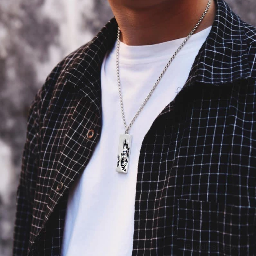 Buddhist amulet necklace close-up neck wear - silver Buddha pendant on thin chain held by fingers