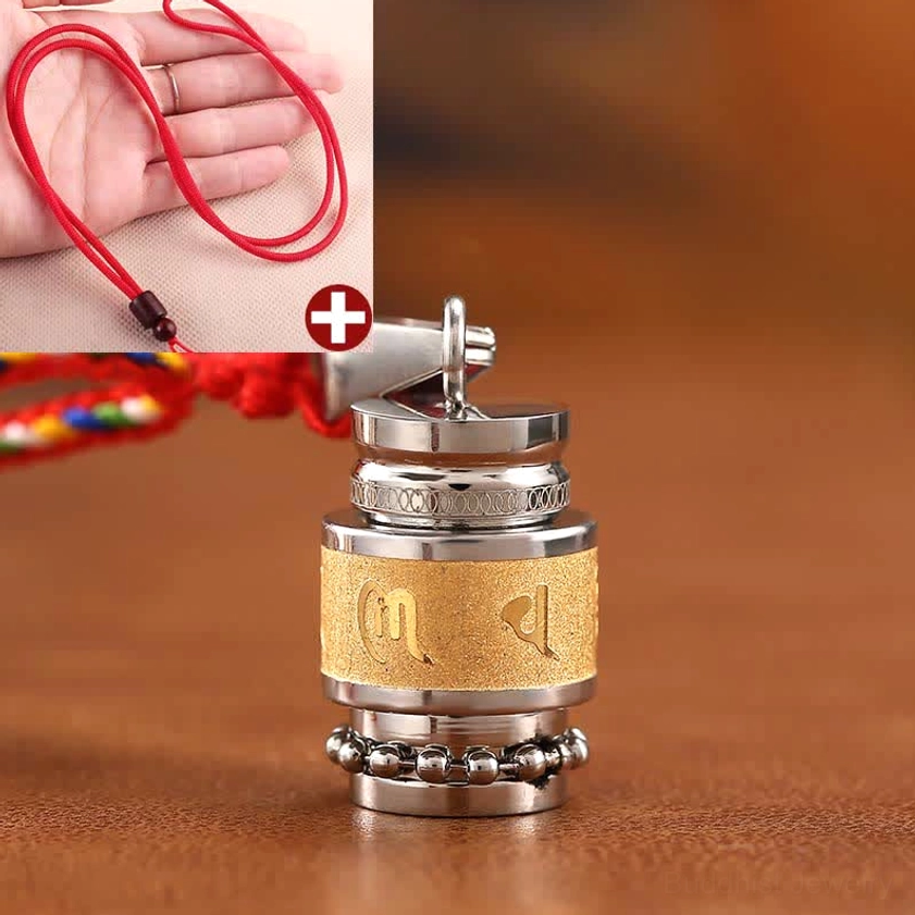 Buddhist prayer wheel amulet pendant with red simple woven lanyard held in hand showing mantra design