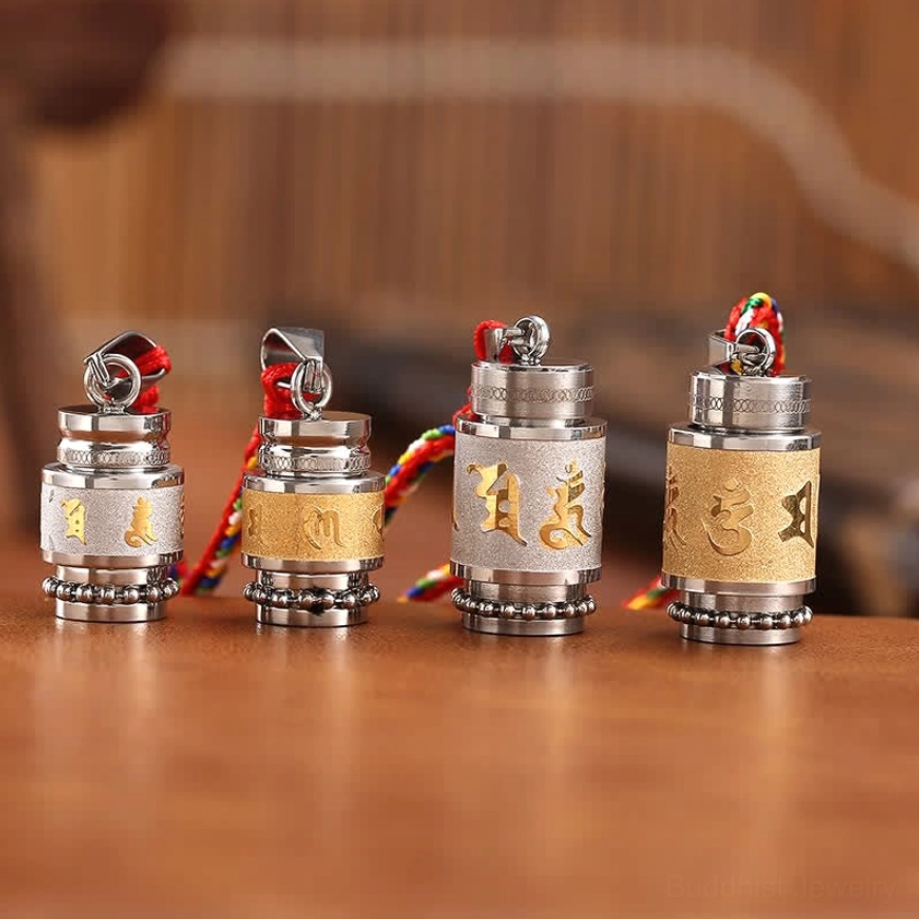 Set of four buddhist prayer wheel amulet pendants with mixed silver and gold engraved mantras static group shot