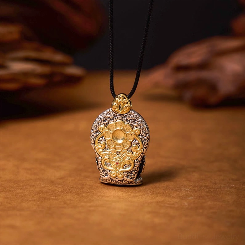 Buddhist Avalokitesvara floral amulet pendant with intricate gold carving and silver metal base on wooden surface