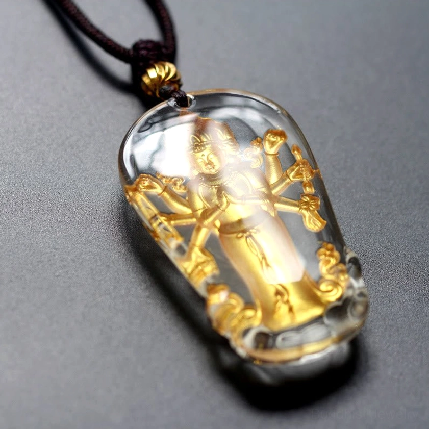 Eight-armed Avalokitesvara Buddhist pendant necklace side view showing crystal encasement reflection and brown cord with gold accent