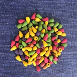 Mixed color Buddhist backflow incense cones in vibrant hues arranged on blue woven fabric, showing variety of scent options for meditation practice