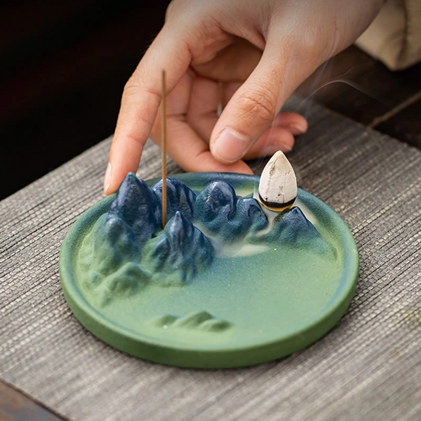 Ceramic Buddhist backflow incense holder with active incense cone showing flowing smoke cascade and ritual aromatherapy benefits