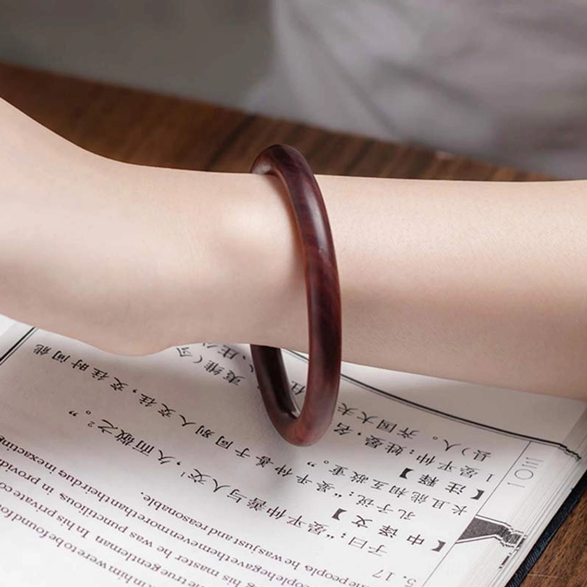 Dark Reddish-Brown Buddhist Wood Bangle on wrist with vintage paper - showing round smooth shape and fit