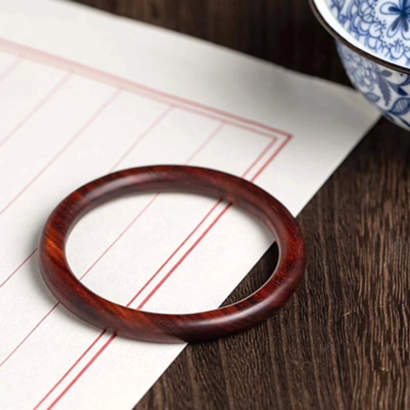 Reddish-Brown Wood Buddhist Bangle flat lay on vintage paper - top-down view showing polished edge and grain
