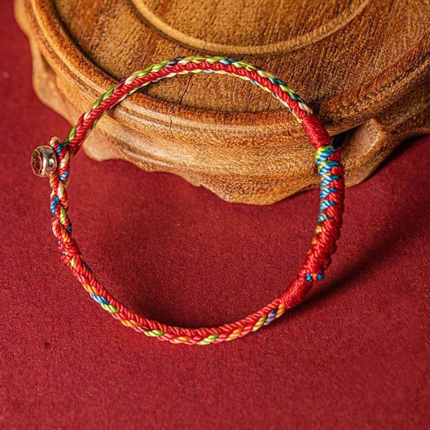 Handmade Buddhist protection bracelet with adjustable metal clasp, three-quarter view showing braided texture and color symbolism