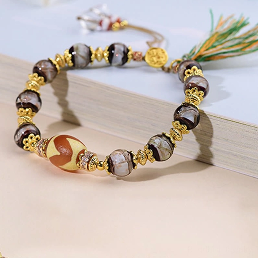 Premium liuli glass dzi bracelet on wooden book stand showing tiger-tooth dzi bead and metal accents