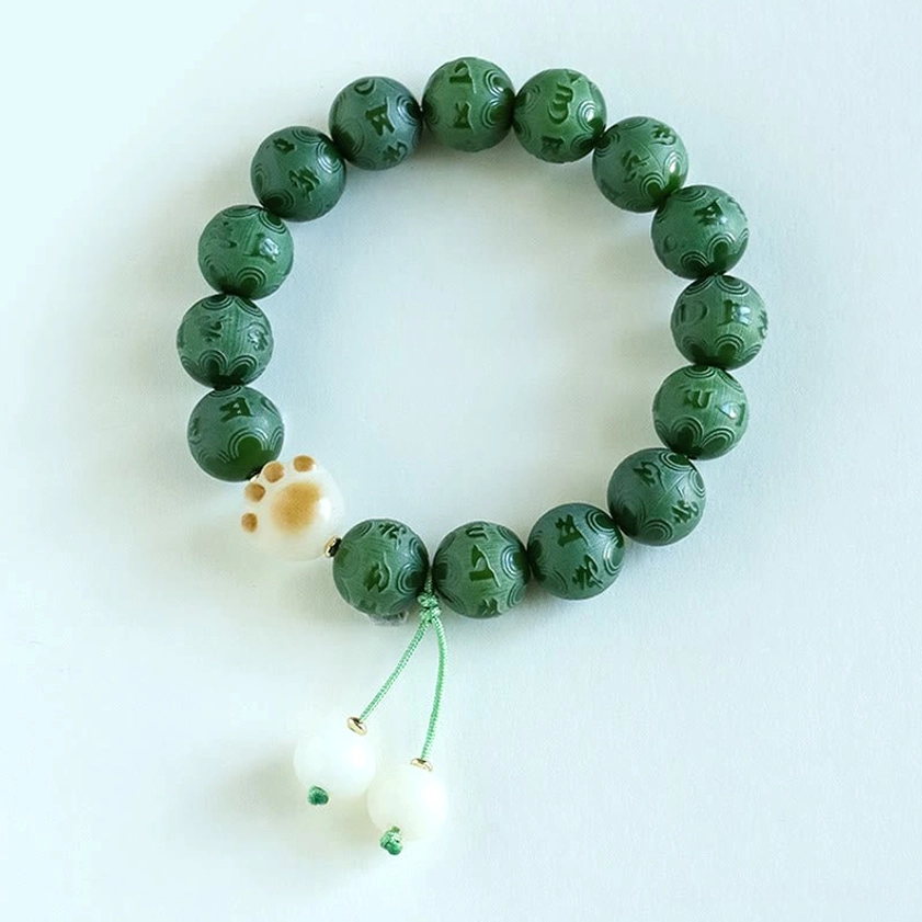 Circular arrangement of dark green Bodhi Seed bracelet with intricate Om Mani Padme Hum carvings and matching tassel charms