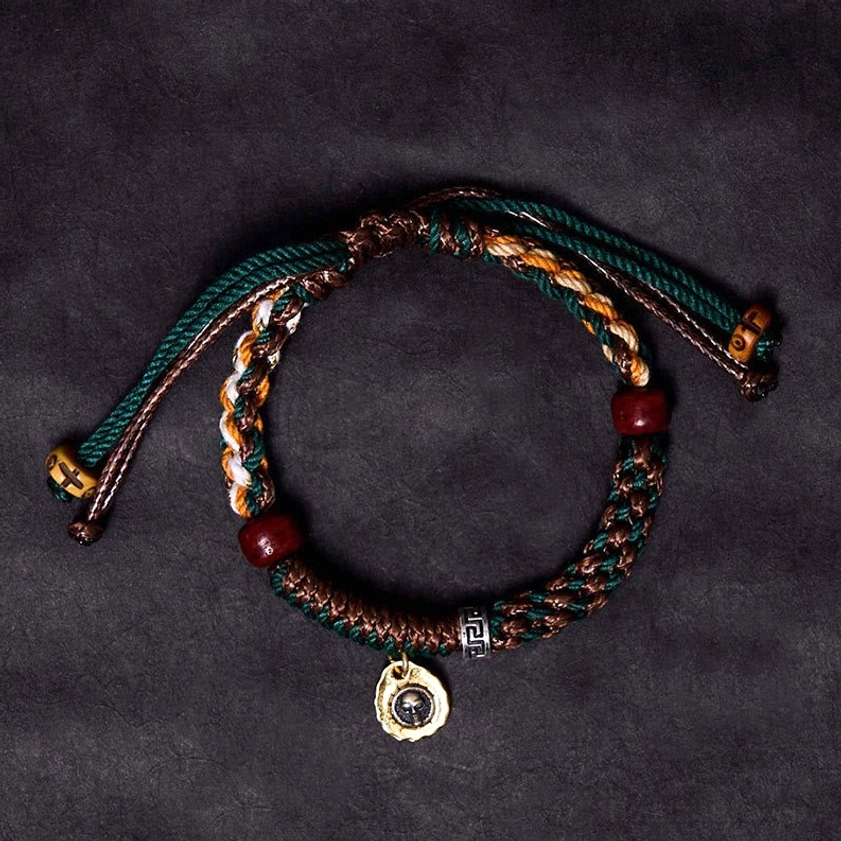 Double-layer Buddhist bone bead bracelet with green and brown woven rope, red wooden beads, and engraved metal pendant - flat lay