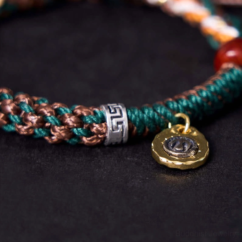 Close-up macro shot of Buddhist bone bead bracelet showing detailed braided rope texture, silver fastener, and engraved metal charm