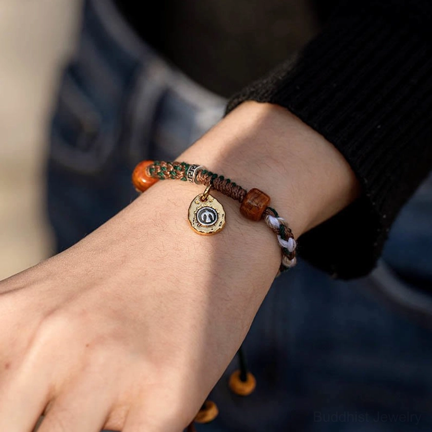Buddhist string bracelet worn on right wrist with brown and white mixed rope, bone beads, and adjustable drawstring knot