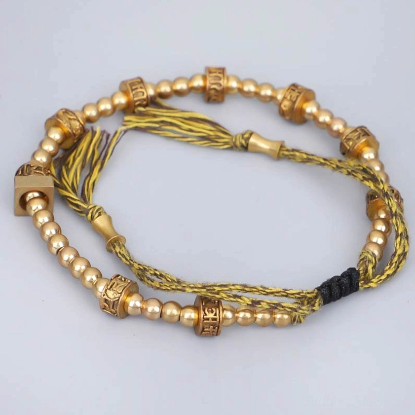 Adjustable Buddhist bracelet showing yellow-brown mixed tassel cord and black sliding knot fastener