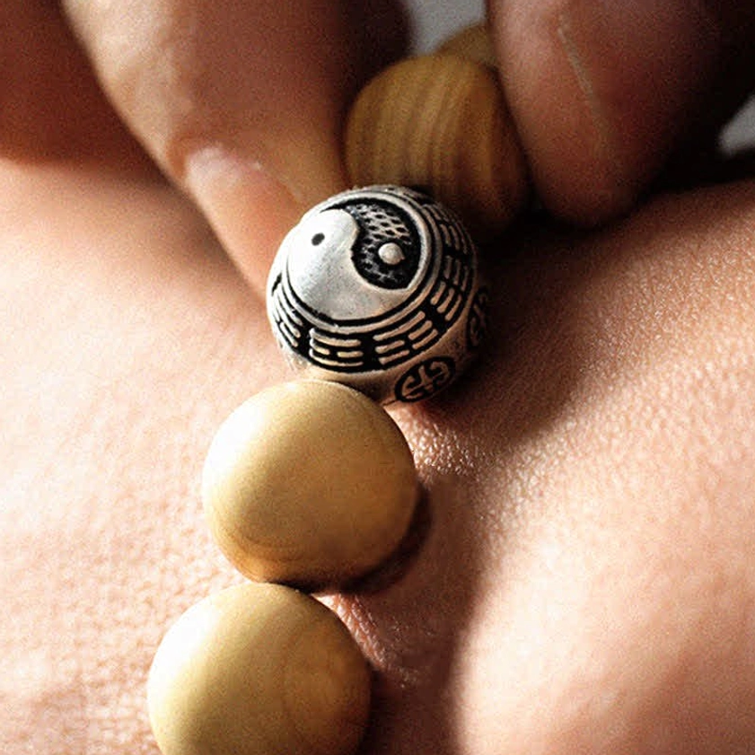 Extreme close-up of engraved silver bagua and yin yang bead detail on Buddhist bracelet