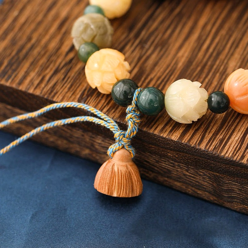 Partial view of spiritual bodhi seed bracelet with carved floral beads and braided cord detail