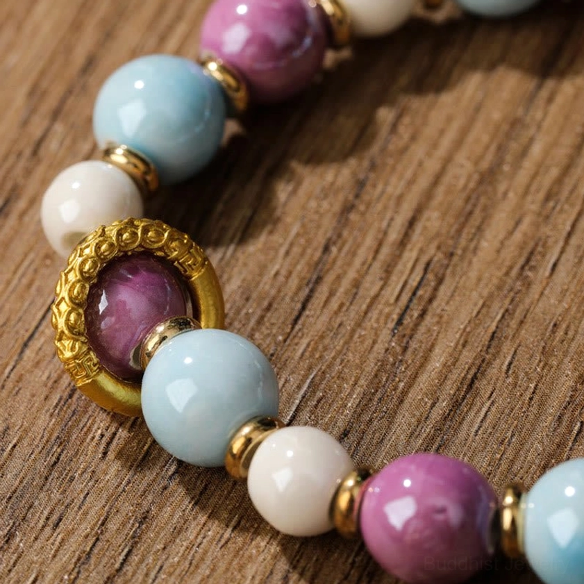 Detailed macro photography of Buddhist prayer bracelet beads showing mixed pastel colors with gold metal ring spacers and purple stone accent