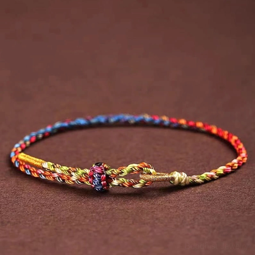 Lucky multicolor braided Buddhist string bracelet with central decorative knot, flat weave design