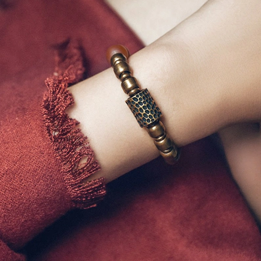 Handcrafted Buddhist bracelet with bronze spacer beads and natural gemstone on red fabric