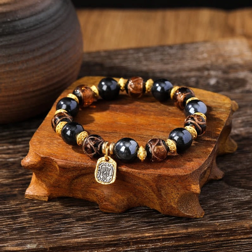 Brown-toned Buddhist prosperity bracelet with warm earth-colored Liuli glass beads and protective engraved metal pendant
