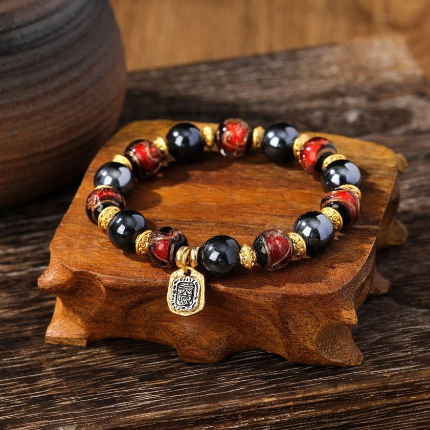 Brown and navy toned Buddhist wealth bracelet featuring earthy Liuli glass beads with gold spacers and protective pendant