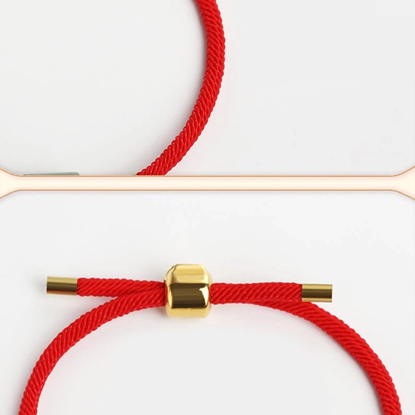 Close-up of braided red rope Buddhist bracelet showing gold metal sliding clasp and adjustable cord ends on white background