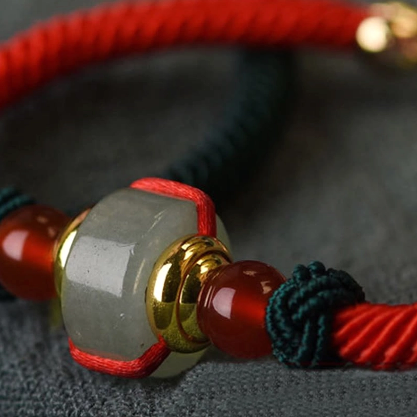 Macro photography of green aventurine bead, red agate, and gold metal components of Buddhist bracelet