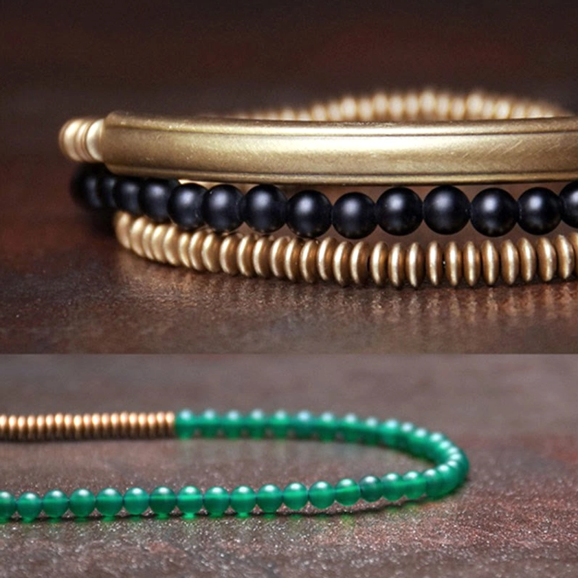 Buddhist bracelet components flat lay showing individual black beads copper metal spacer tubes and brass accessories on dark wooden surface