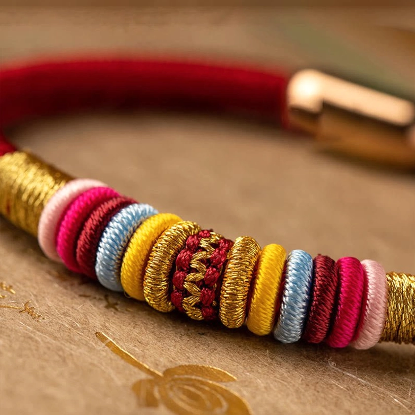 Extreme close-up of Buddhist bracelet decorative beads in gold and multicolor woven design