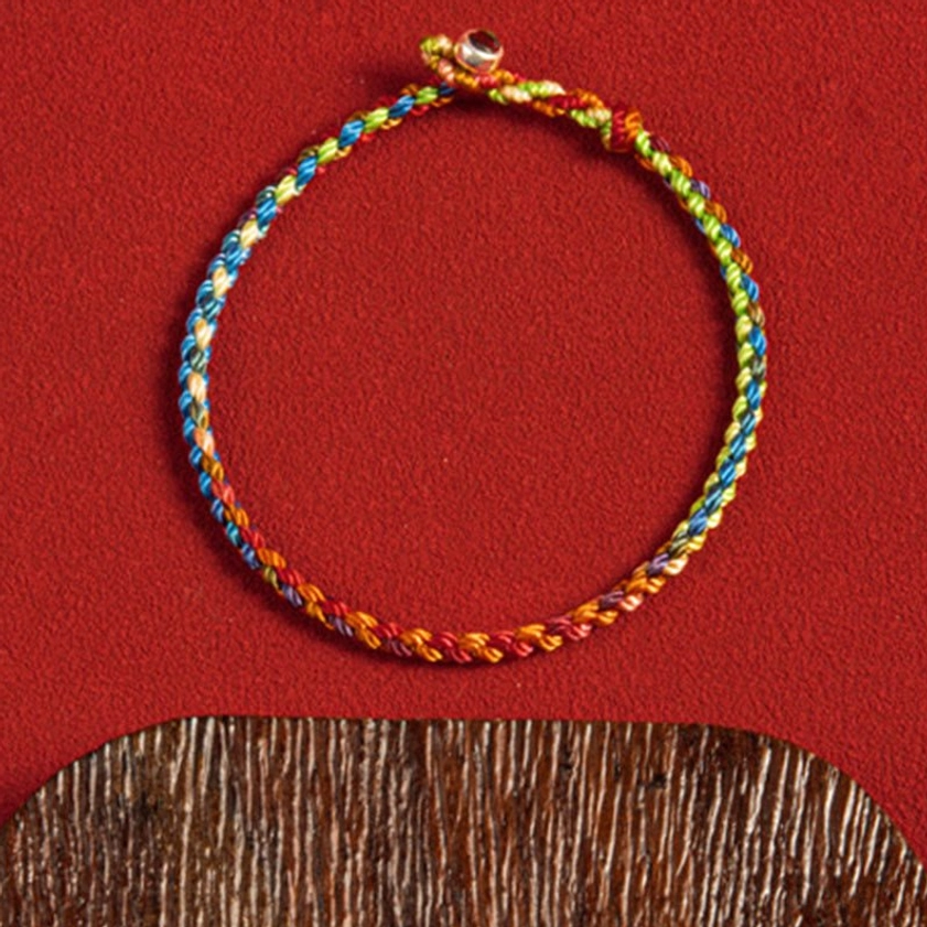 Handmade multicolored Buddhist bracelet close-up showing detailed cord weaving and silver clasp design