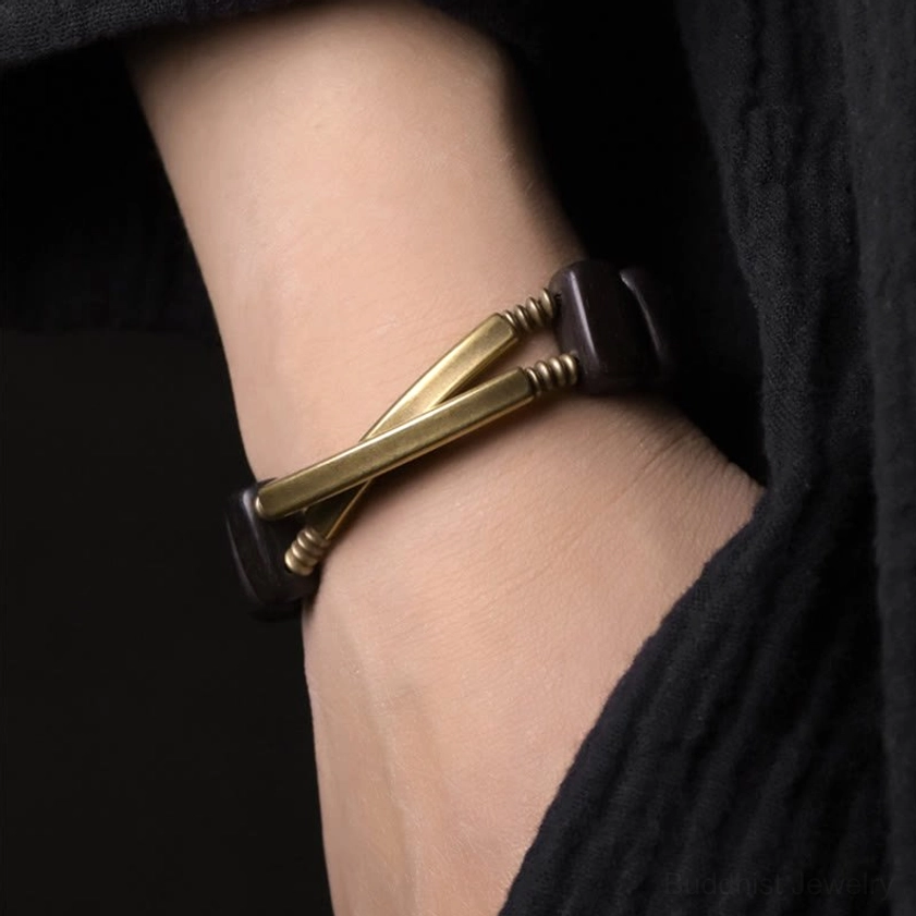 Double-layer Buddhist bracelet on wrist with crossed brass metal bars and ebony wood beads detail