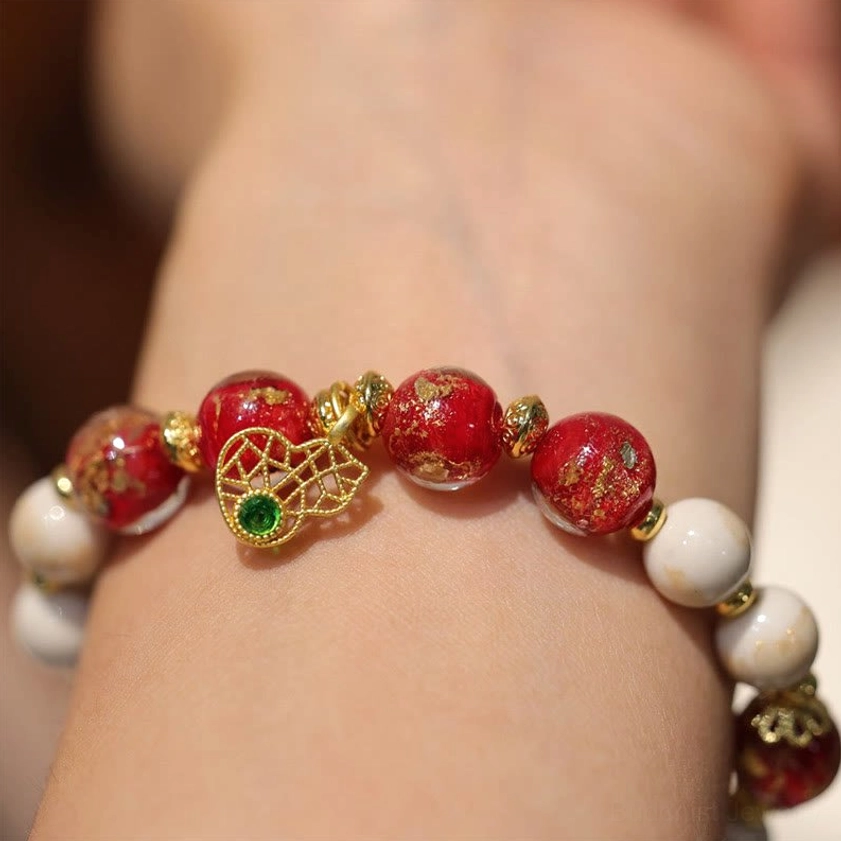 Wrist view of gold gourd wealth charm Buddhist bracelet with mixed red, white, and gold beads worn on skin
