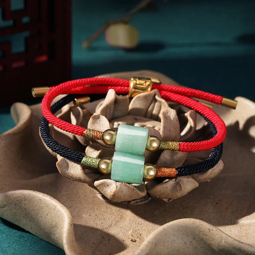 Handcrafted Buddhist string bracelets with gemstones placed on ceramic lotus ornament showing dual green aventurine beads with adjustable gold clasp