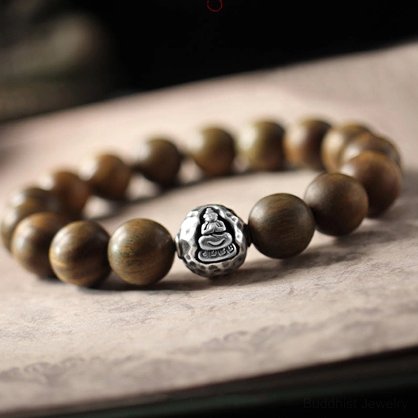 Green sandalwood and sterling silver Buddhist bracelet with engraved Buddha charm, top-down view showing smooth wooden beads and matte silver detail