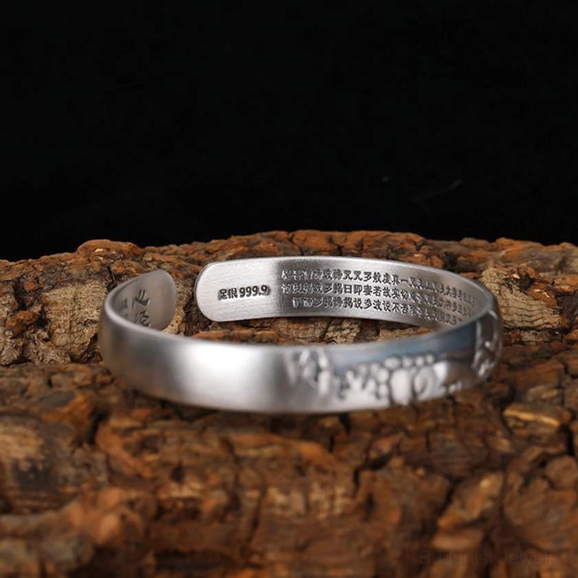 Flat top-down view of 999.9 sterling silver Buddha cuff bracelet, smooth matte finish with outer Buddha pattern, inner sutra and silver hallmark