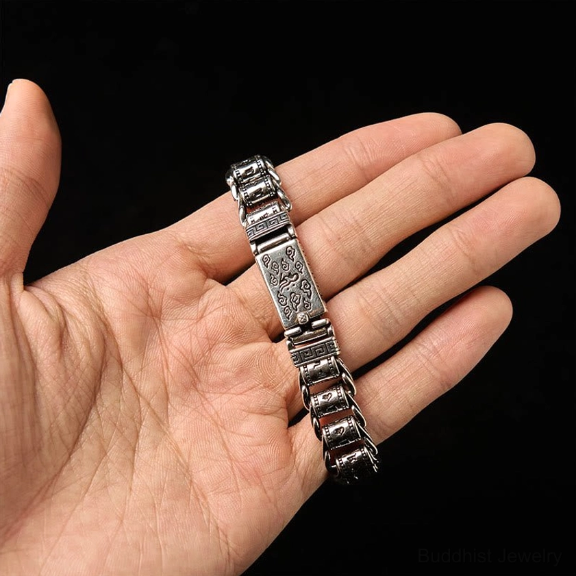 Eye-level hand perspective of antique copper bracelet with detailed Tibetan script engravings resting on palm
