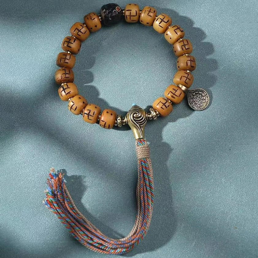 Handcrafted Buddhist bracelet featuring bone beads, metal toggle clasp, round spiritual pendant, and neat woven tassel