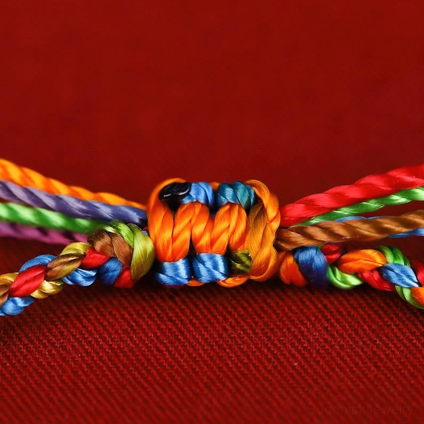 Handmade Buddhist string bracelet knot detail showing vibrant multicolored weave and traditional knotting technique
