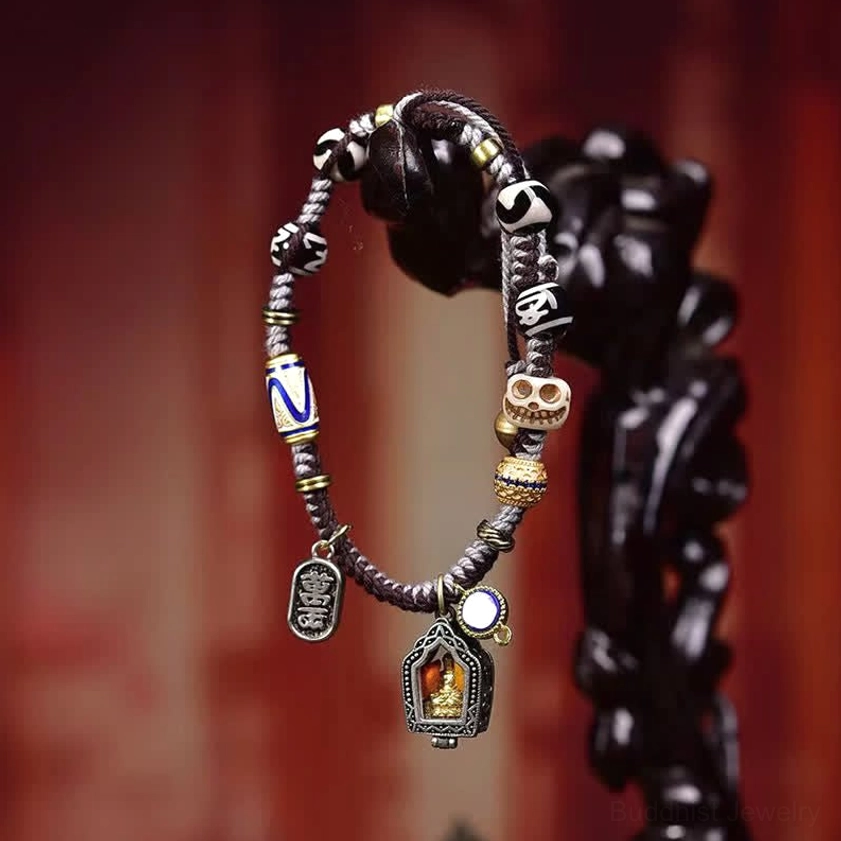 Handmade Buddhist rope bracelet displayed on wooden background showing silver-toned Buddha pendants with blue enamel accents