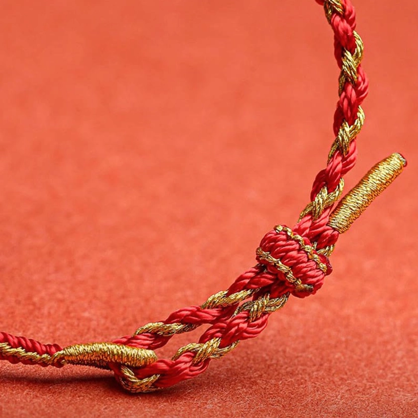 Close-up macro detail of twisted red-gold braided Buddhist protection bracelet knot