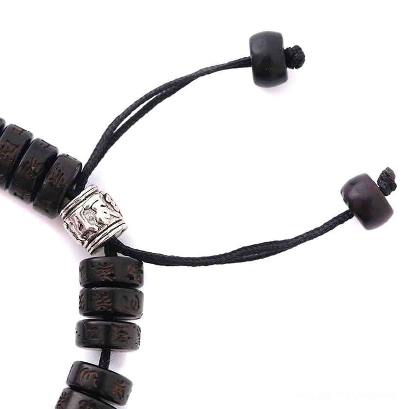 Close-up macro detail of coconut shell bracelet showing carved silver Buddhist charms and natural bead texture