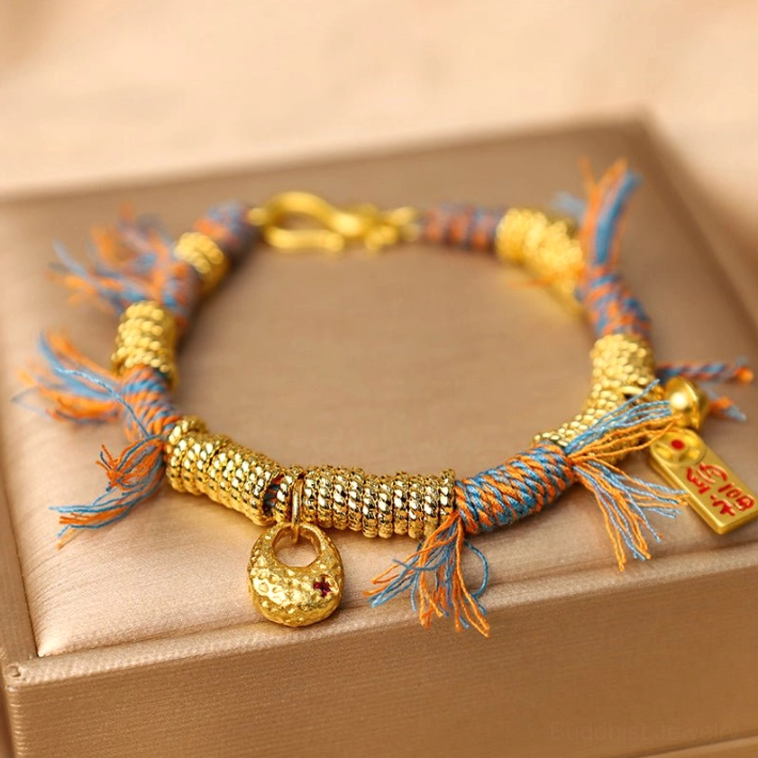 Buddhist fortune bracelet close-up detail shot revealing gold-toned woven tube beads, metal clasp mechanism, and premium string construction on neutral background