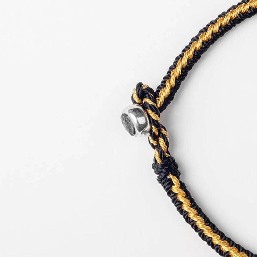 Close-up macro detail of handmade Buddhist string bracelet clasp and braided natural rope fibers with metal buckle