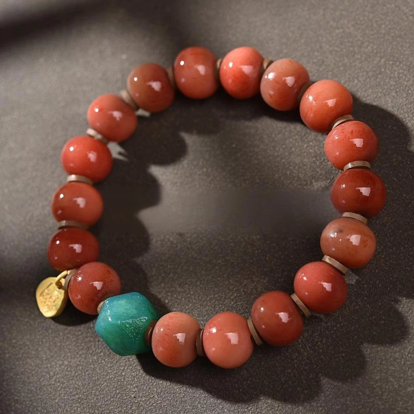 Buddhist protection bracelet design featuring turquoise dzi bead accents, gold copper metal charms, and matte red agate beads on elastic string for daily wear