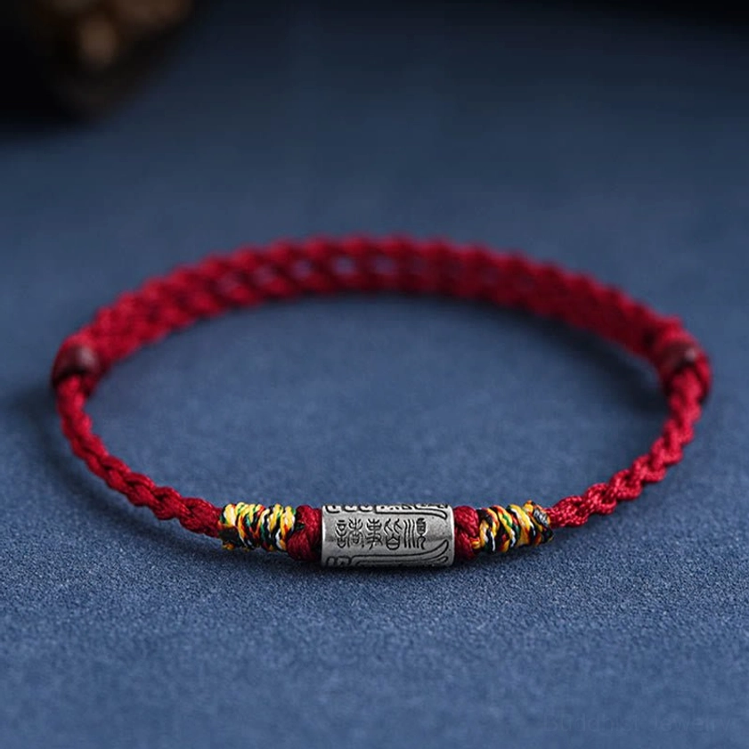 Flat lay overhead view of Buddhist blessing bracelet showing complete design, rope weave pattern, and sterling silver charm arrangement