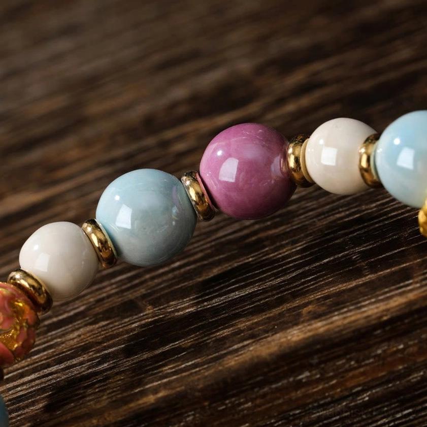 Macro close-up of Buddhist bracelet bead composition featuring blue, purple, and white porcelain beads with gold metal spacer components