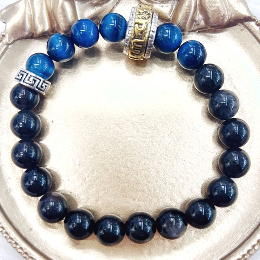 Silver sheen obsidian blue tiger eye bracelet arranged on white satin jewelry box lining