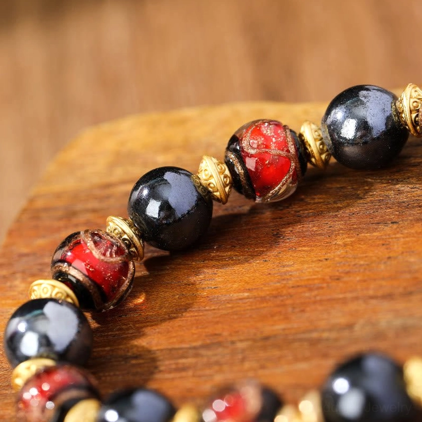 Detailed macro view of red glazed Liuli glass and black porcelain beads with gold-plated spacers on Buddhist wealth bracelet